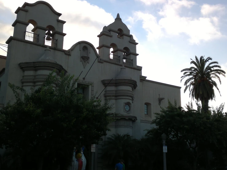 a church with clocks and spires next to some trees