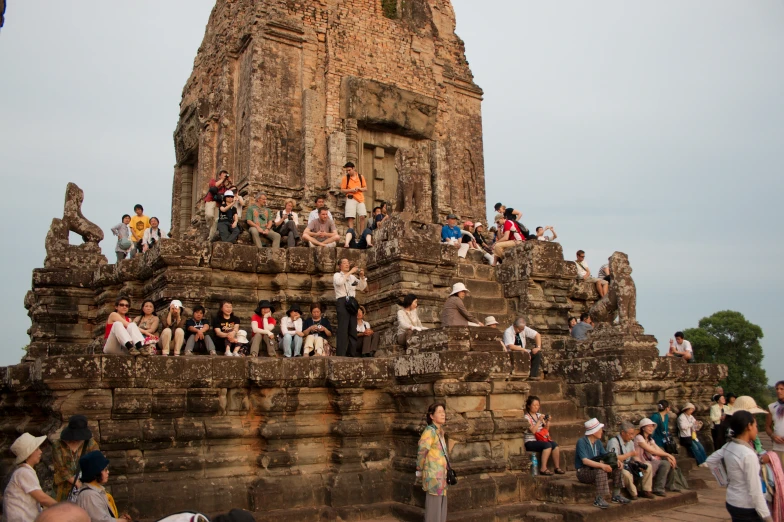 many people sitting on the steps near the entrance to an elaborately built temple