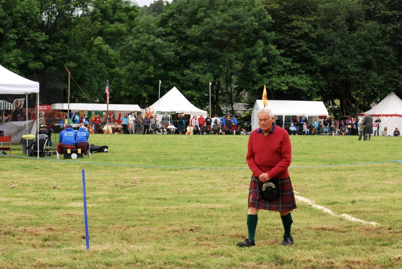 a man in a kilt standing on the grass