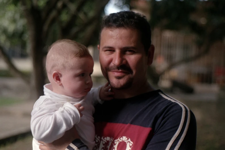 a man holds his baby in the park