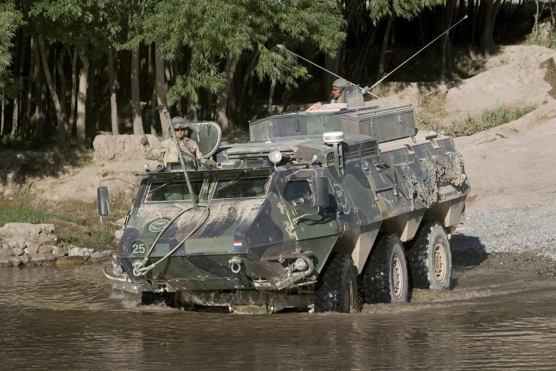 two men in camouflage jackets and vests stand inside an army armored vehicle