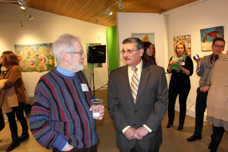 a man in a striped sweater is talking to an older gentleman