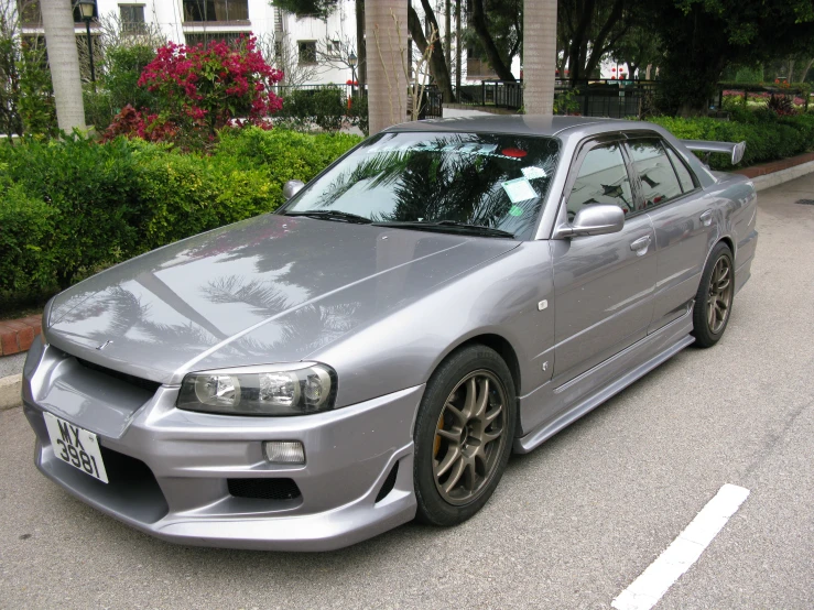 the car is shiny and silver near bushes