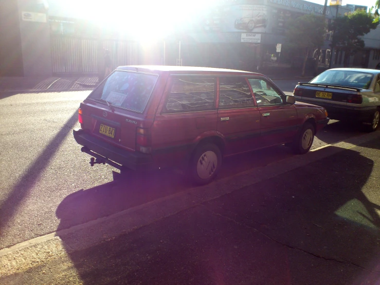 a red station wagon with a few black cars behind it