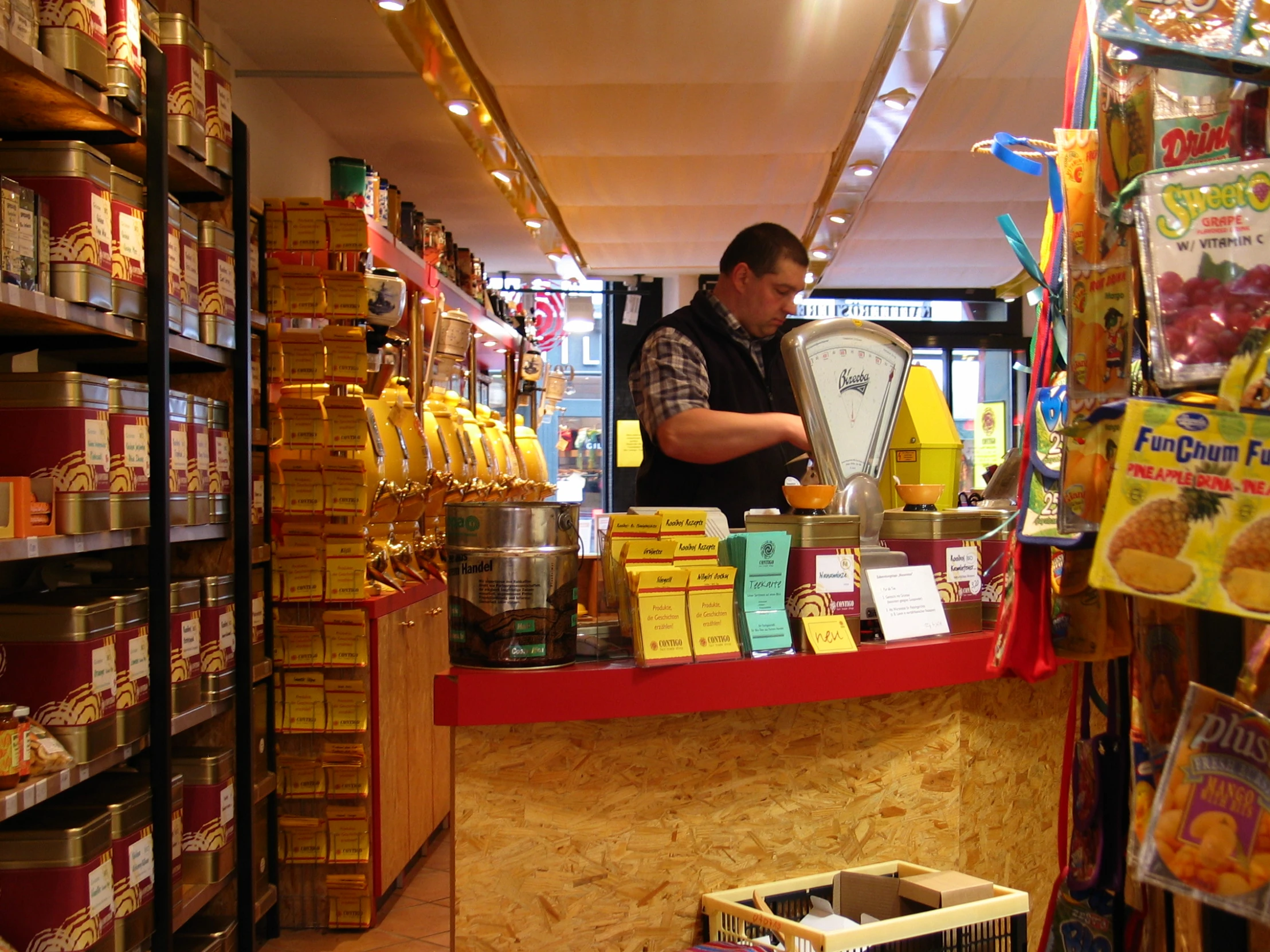 a man behind a cash register with goods behind him