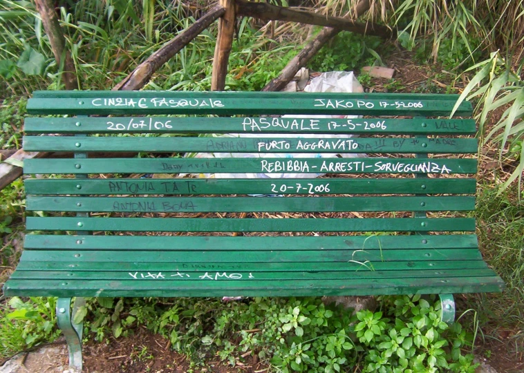 a green wooden bench with some writing on it