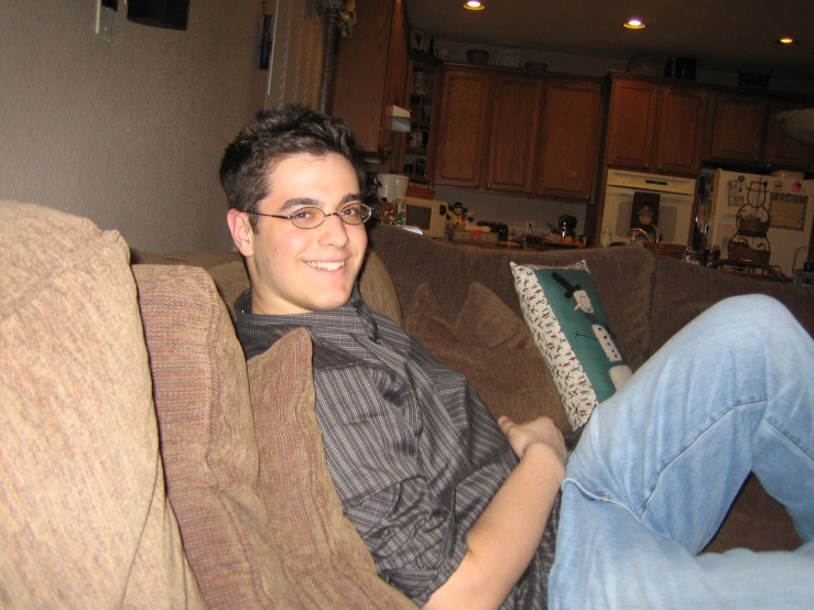 a young man sitting on a couch with a striped tie