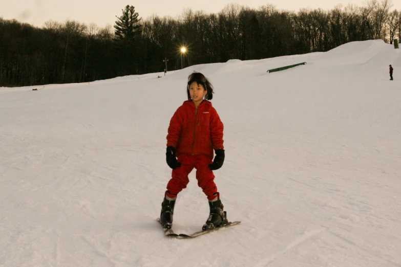 a young child in a red snowsuit on a snowy slope