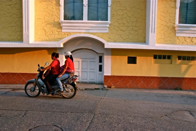 two people in red shirts on a motorcycle