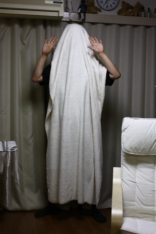 a man wrapped in a white towel standing by a window