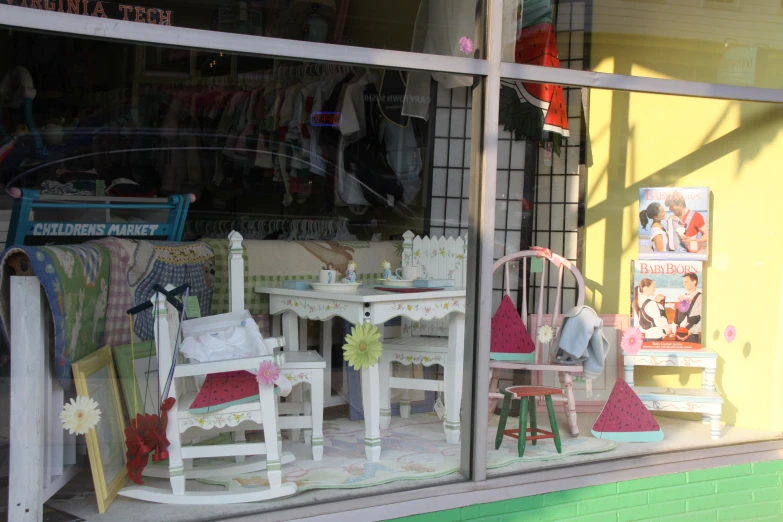 the view of a colorful clothing store window shows children's clothes, and dolls