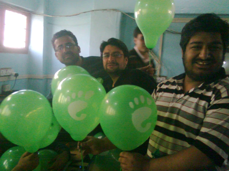 a group of people holding green balloons with a drawing on them