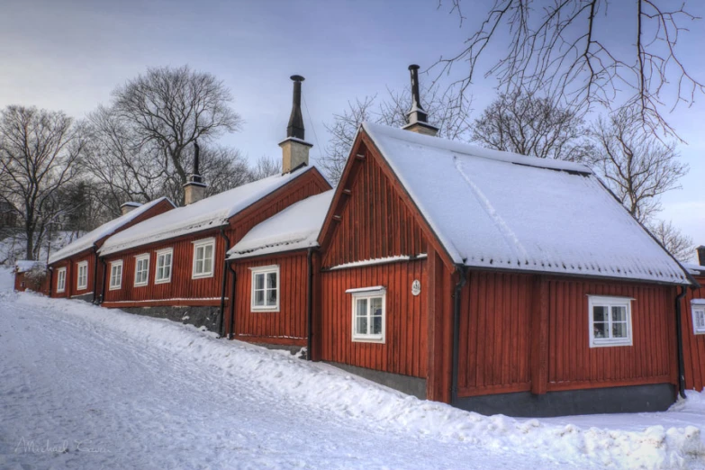 a row of red buildings on a snowy road