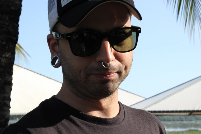 man with ear studs, hat and sunglasses on