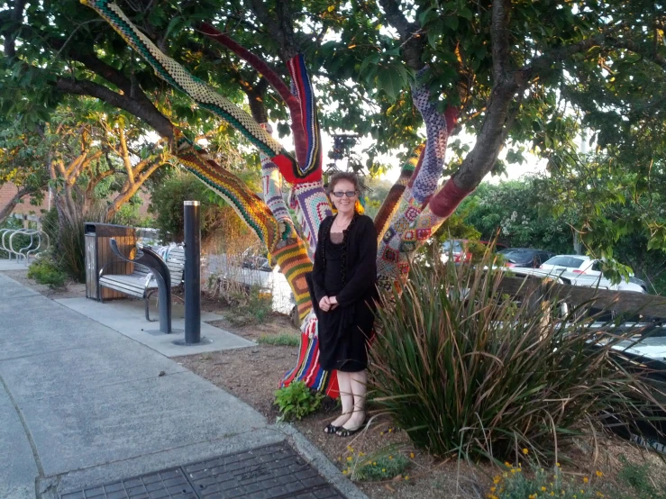 a woman standing by a colorful tree with a big dragon sculpture