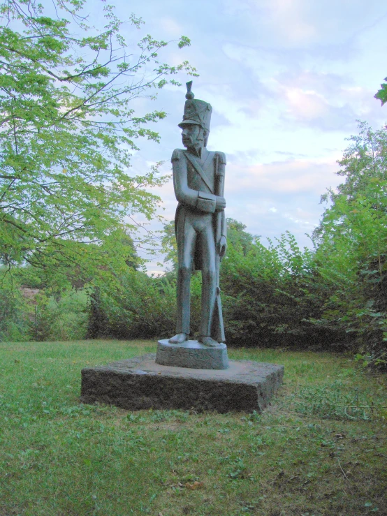 a statue in the grass near a bush