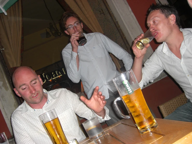 two men are sitting and drinking beer at a restaurant