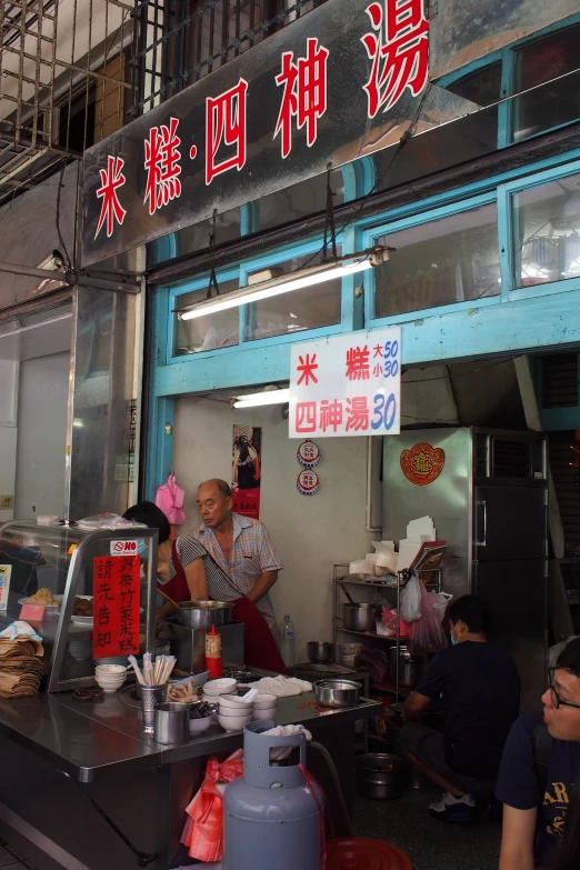 people in a small outdoor restaurant near chinese writing