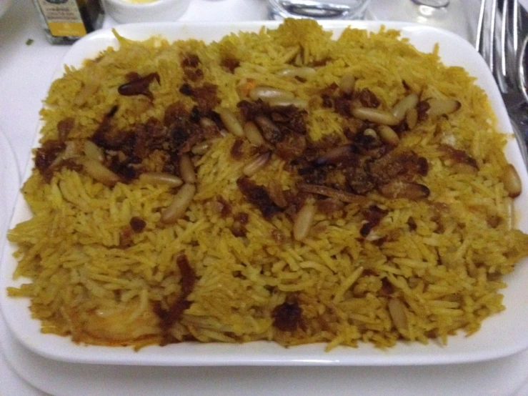 rice in a white plate is served with nuts