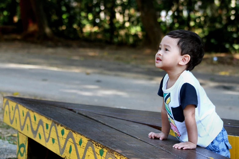 a small boy is sitting on a wooden bench