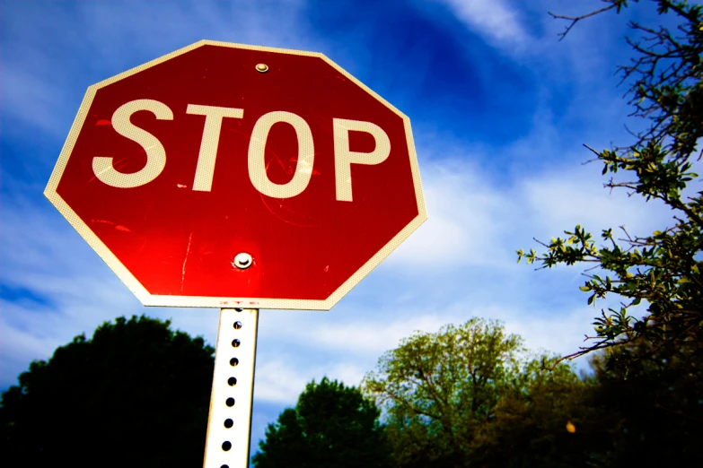 a closeup po of a stop sign with trees in the background