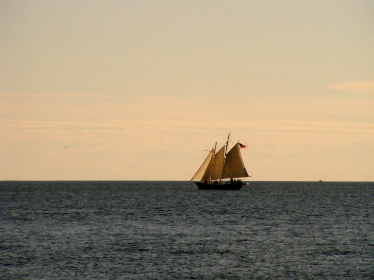 a sailboat sailing on the water at dusk