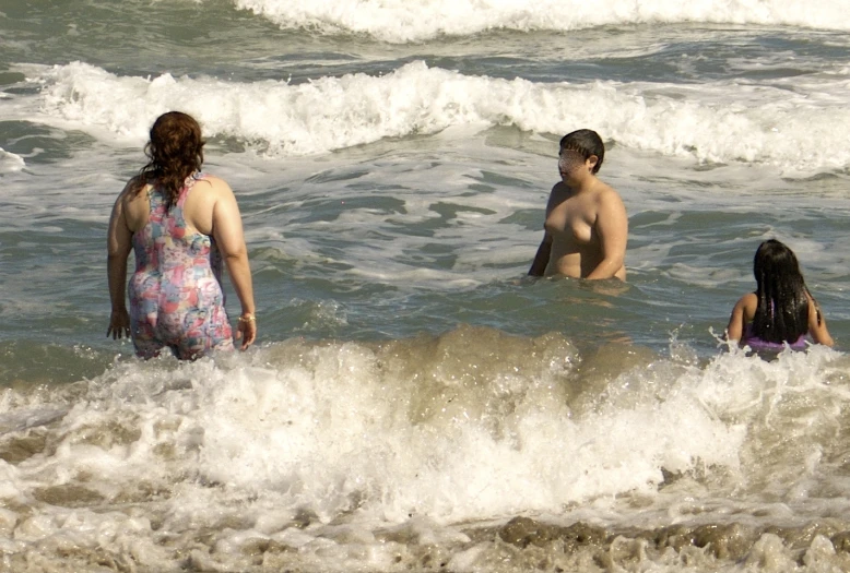 a group of people standing in the water at the beach