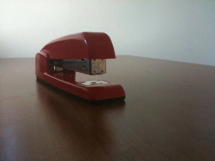 a red plastic puncher sits on a table