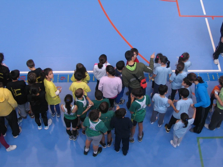 a crowd of children standing on a tennis court