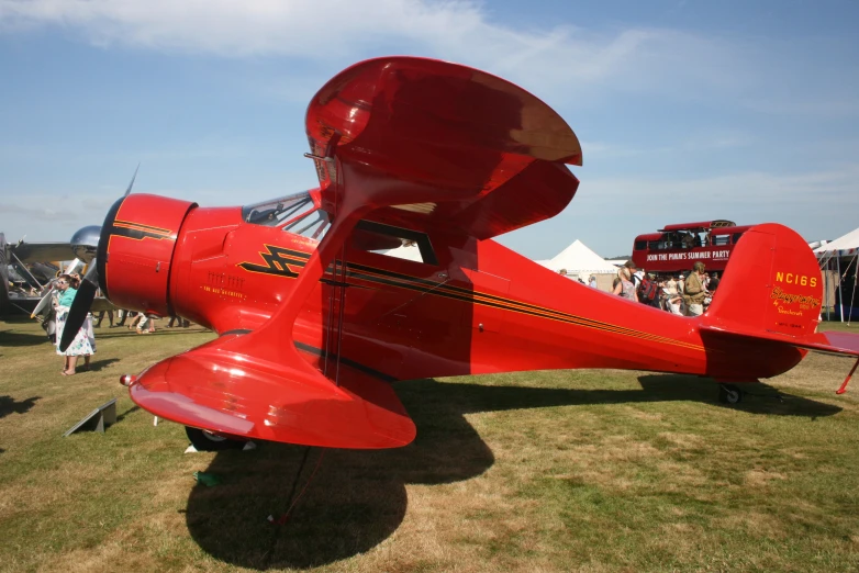 the red airplane sits on the grass on display