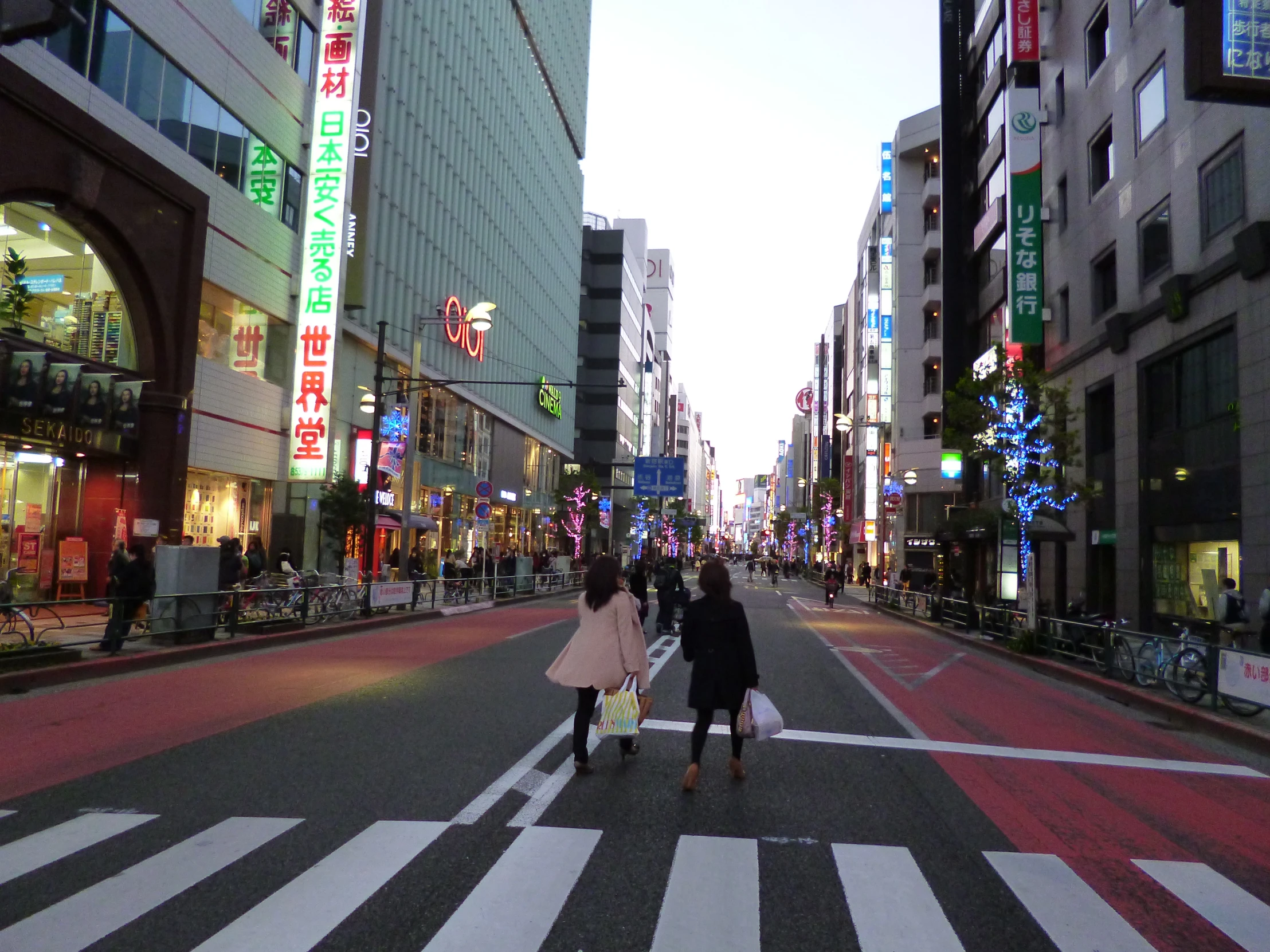 two women walking across a street with neon lights