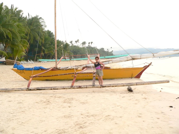 a girl stands next to a boat that has been tied up on the beach
