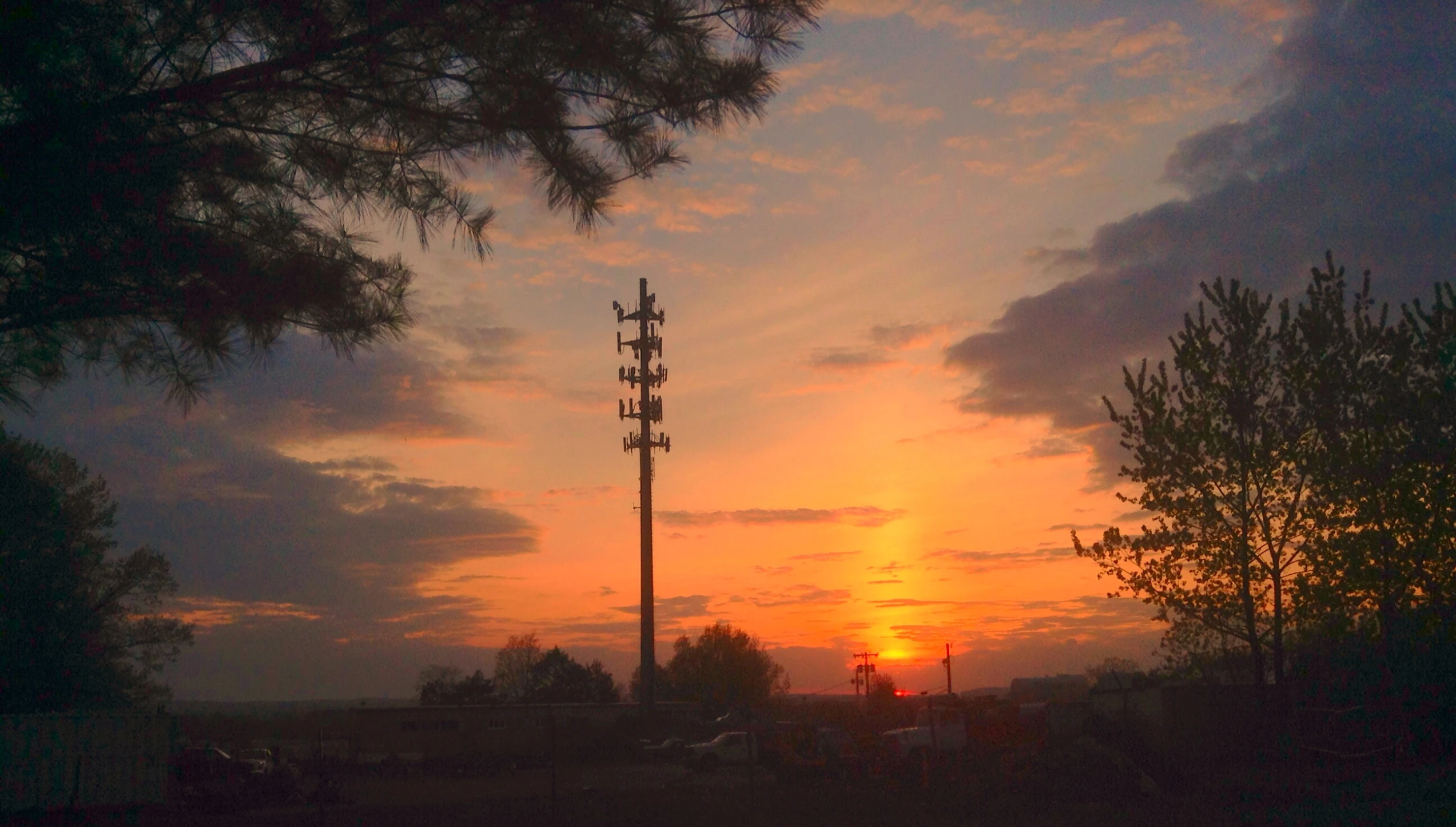 the sun is setting behind the cell towers