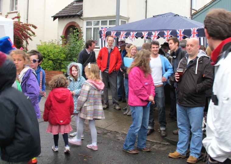 a group of people standing in the rain by a house