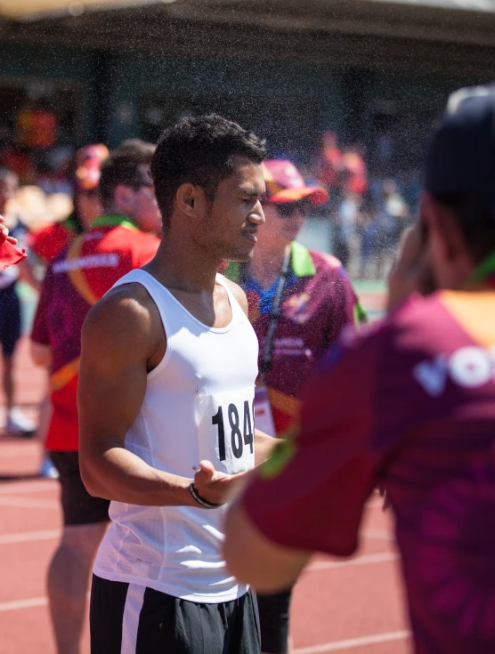 a male athlete getting sprayed from a spray bottle