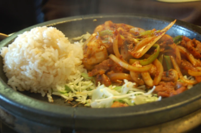 some rice and meat on a plate with vegetables