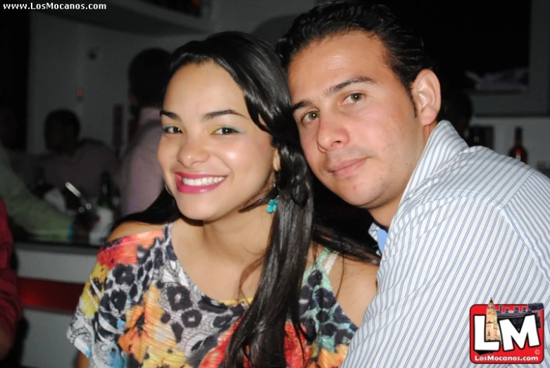 a couple posing for a picture in a crowded bar