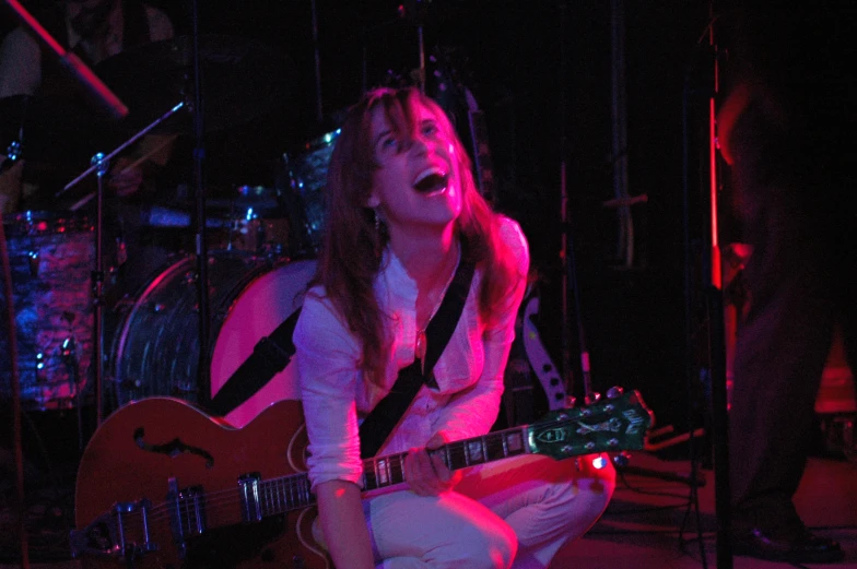 woman playing a guitar in front of microphones