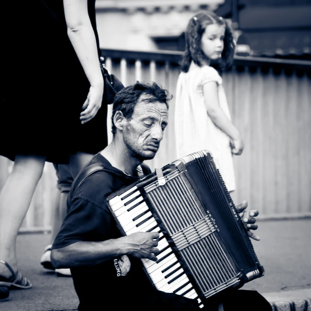 a man sitting on the ground while playing an accordian