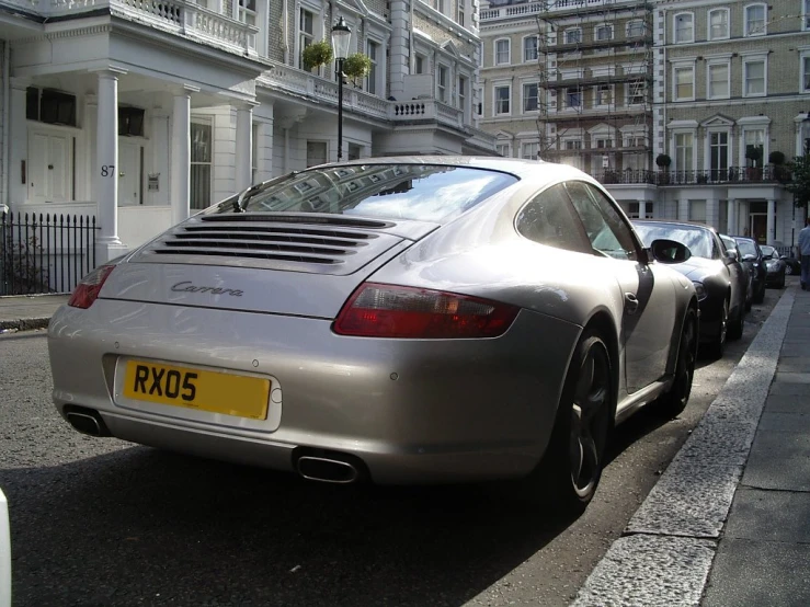 a silver porsche car is parked on the sidewalk