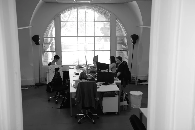 a large window next to the desk is filled with people