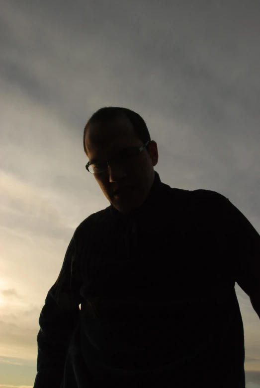 a man with glasses standing on the beach looking at soing