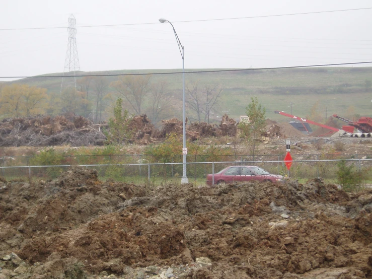 an area with dirt and vegetation, a fence and some houses