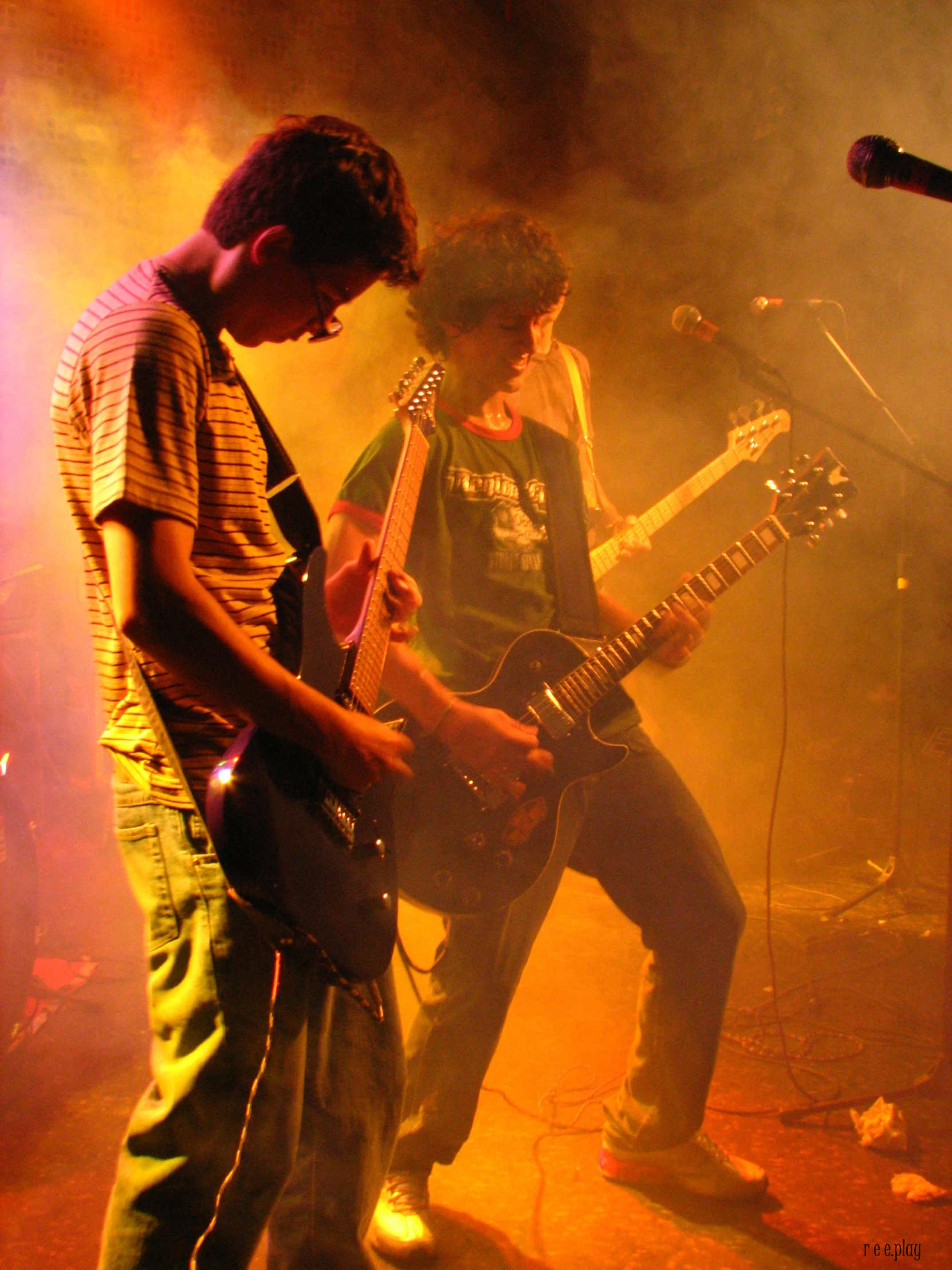 two young men are playing instruments on stage