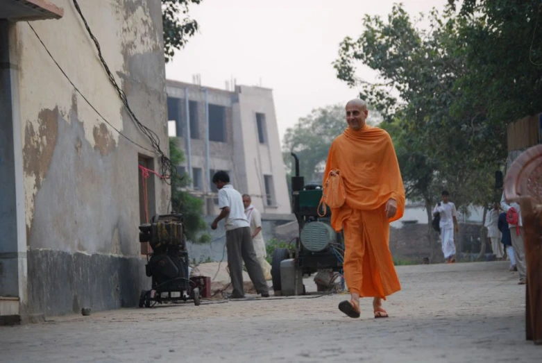 a man walking down the road with an orange outfit