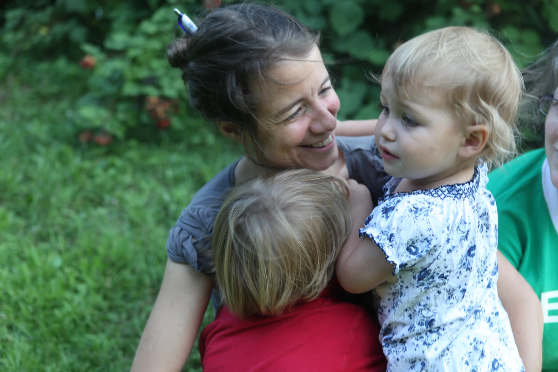 a  with a tooth brush on her head sitting on the shoulder of a lady and three other children