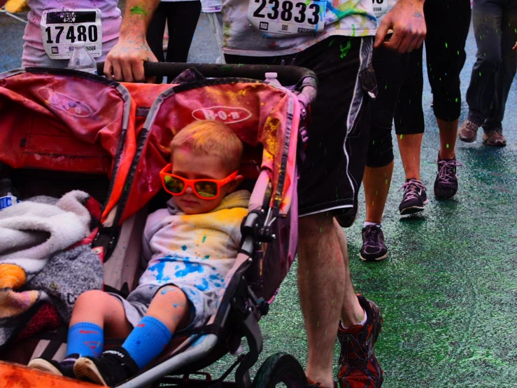 a toddler in a stroller and many other people