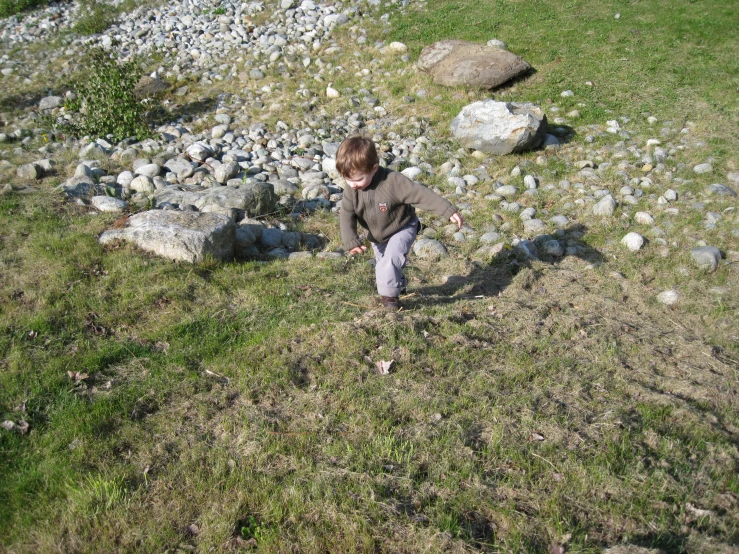 a small boy stands on some rocks near the water