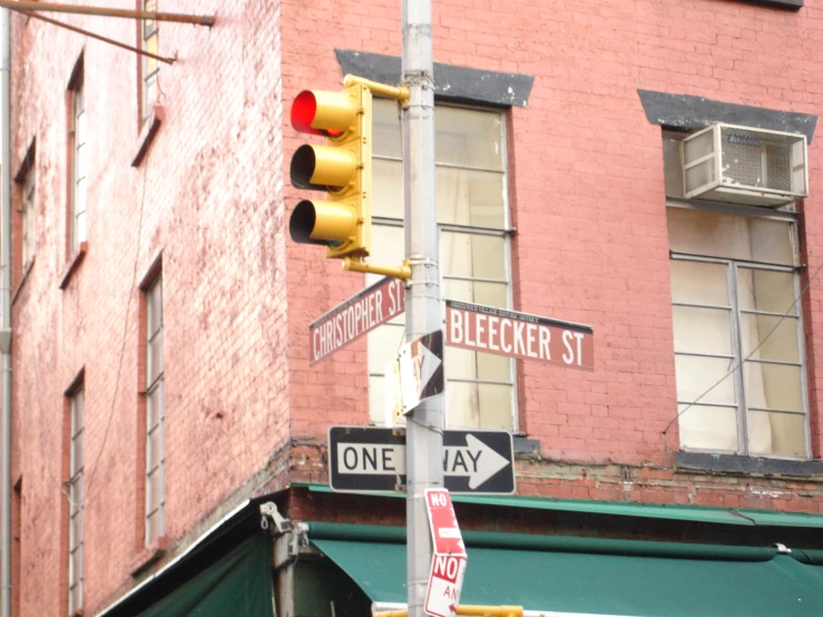 several street signs are posted in front of a red brick building