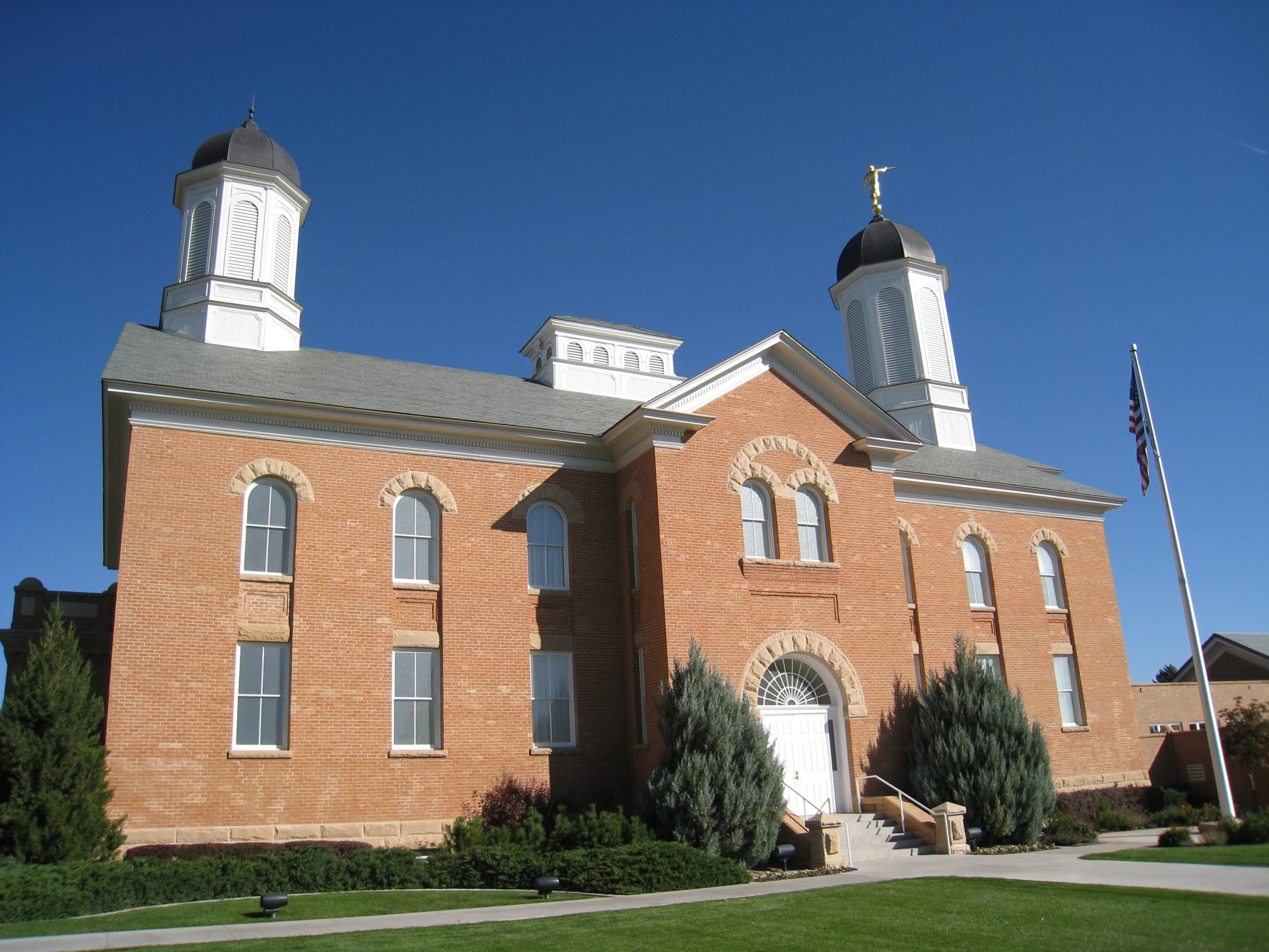 a brick building has two towers and is surrounded by grassy lawn